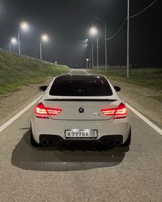 a white car parked on the side of a road at night with street lights in the background