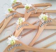 a bunch of wooden clothes hangers with flowers on them and names written on them