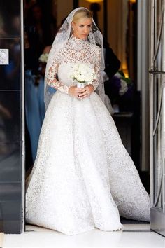 a woman in a wedding dress is walking out of the church with her veil pulled back