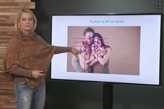 a woman standing in front of a projection screen pointing to the side of her face