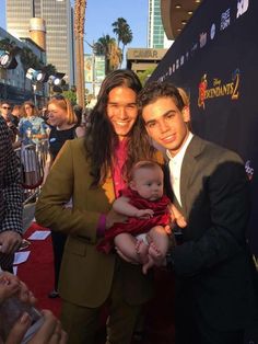 two men and a baby posing for a photo on the red carpet at an event