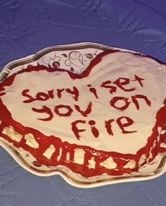 a heart shaped cake with the words sorry i love you on fire written in red icing