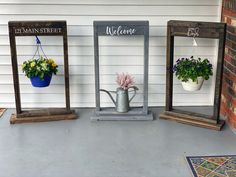 three planters with flowers in them are sitting on the side of a building next to a sign that says welcome