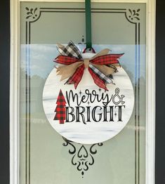 a merry and bright sign hanging on the front door window with a green pole next to it