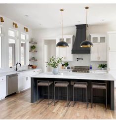 a large kitchen with white cabinets and black island in the center is surrounded by stools