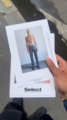 a person holding up a piece of paper with an image of a shirtless man on it