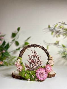 a miniature mirror with flowers on it sitting in front of some leaves and branches,