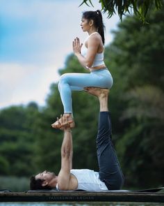 a man and woman doing yoga on the water