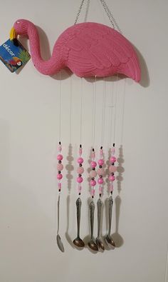 a pink flamingo wind chime with spoons and forks hanging from it's side