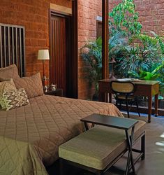 a bedroom with a bed, chair and desk in front of a window that looks out onto the jungle