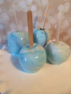 four blue apples on a white plate with toothpicks sticking out of the top