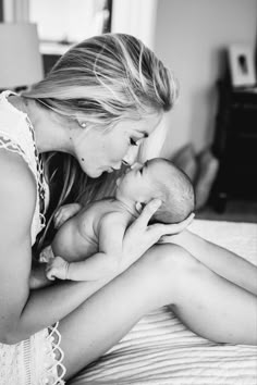 a woman is holding her baby while laying on the bed