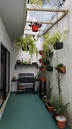 an outdoor patio with potted plants on the wall and a grill in the middle