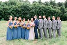 a group of people standing next to each other in a field with trees behind them