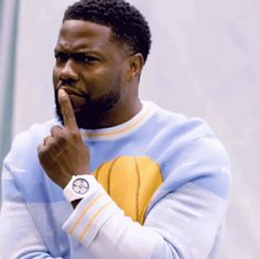 a man in a blue and yellow sweater is holding his finger up to his mouth