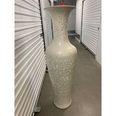 a large white vase sitting on top of a cement floor next to storage units in a building