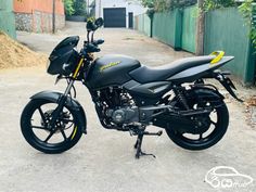 a black motorcycle parked on top of a dirt road