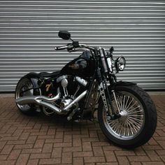 a black motorcycle parked on top of a brick floor next to a garage door with roller shutters