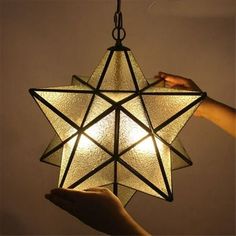 a person is holding up a star shaped light fixture