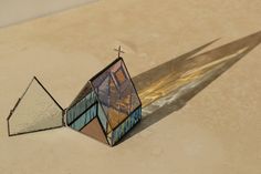 a small stained glass object sitting on top of a table next to a cross and window