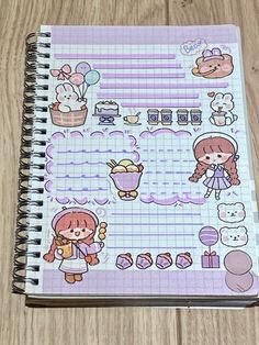 a notebook with stickers on it sitting on top of a wooden table next to a pen