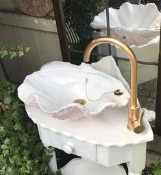 a white sink with gold faucet sitting on top of it's stand