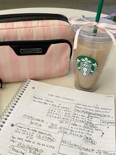 a cup of coffee next to a pink and white striped bag with writing on it