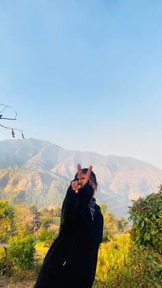 a person standing in front of mountains making the peace sign