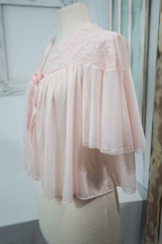 This sweet vintage woman's bed jacket is very soft sheer pink with pretty lace accents and a satiny bow to close the front. It's really perfect, with no damage, stains, or other issues. Please check measurements carefully! Condition: Excellent Vintage Tag: Vanity Fair Measurements in inches... Top of neck to bottom of jacket: 18 Armpit seam to armpit seam: 21 ✩ Because you don't want to miss a thing, follow @heartkeyologie on Facebook and Pinterest and @heartkeyologie.etsy on Instagram for sale Pink Delicate Lace Wedding Night Sleepwear, Feminine Pink Sleepwear With Delicate Lace, Vintage Bed Jacket, Feminine Pink Sheer Sleepwear, Pink Vintage Sleepwear, Pink Sheer Coquette Sleepwear, Vintage Sheer Pink Nightgown, Woman Bedding, Bed Jacket