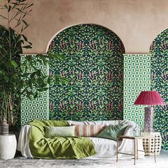 a living room with green and pink wallpaper, a white couch and potted plant