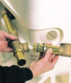 a person fixing a toilet with brass fittings on the side and an opening to it