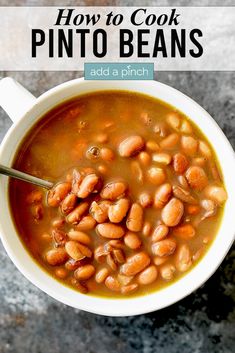 a white bowl filled with pinto beans on top of a gray counter next to a spoon