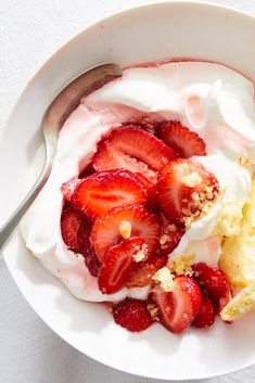 a bowl filled with whipped cream and strawberries next to a muffin on a plate