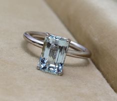 a ring with an aquamarinee stone on it sitting on top of a beige cloth