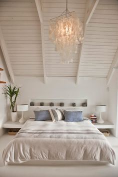 a bedroom with white walls and ceiling, bed has two pillows on the headboard