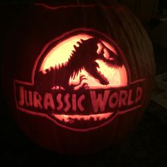 a pumpkin carved to look like a dinosaur with the words,'jurassic world'on it