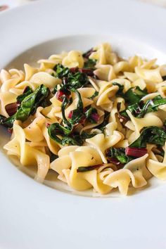 a white plate topped with pasta and spinach