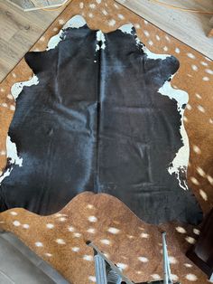 a black and white cowhide rug on top of a wooden floor next to a pair of scissors