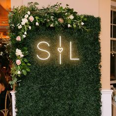 a lush green wall with flowers and greenery around it that reads, i love l