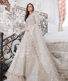 a woman in a wedding dress standing on a balcony next to an iron railing with white flowers