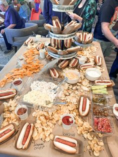 a table topped with lots of hot dogs covered in toppings and condiments