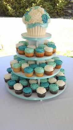 a three tiered cake with cupcakes on it