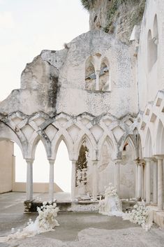 an old building with arches and flowers on the ground