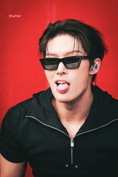 a young man wearing sunglasses making a funny face with his tongue hanging out to the side