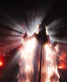 a woman with long hair standing in front of a microphone on stage at a concert