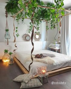 a bed with plants hanging from it's sides and candles on the floor next to it