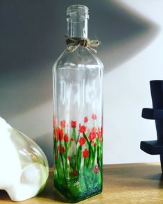 there is a glass bottle with flowers painted on it and a vase next to it