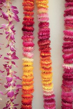 colorful garlands hanging on the wall in front of a white wall with pink and yellow flowers