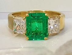 GORGEOUS 18K yellow gold  emerald  ring  NATURAL  GREEN COLOMBIA Emerald ring center emerald shape natural treated green emerald weight 2.05ct.size 9x6.7nice vivid  green color ,clean, very lively ,nice cut .very sparklyside two natural  princess cut diamonds total weight 1.45ct H-SI1Ring SIZE 6.5Retail value $15,500 net.Cert Appraisal available Luxury Green Radiant Cut Rings, Fine Jewelry Green Radiant Cut Diamond Ring, Luxury Green Emerald Ring With Center Stone, Green Radiant Cut Diamond Ring Fine Jewelry, Green Radiant Cut Diamond Ring, Fine Jewelry Green Radiant Cut Ring, Fine Jewelry Radiant Cut Green Ring, Green Radiant Cut Ring Fine Jewelry, Green Radiant Cut Diamond Ring With Gemstone