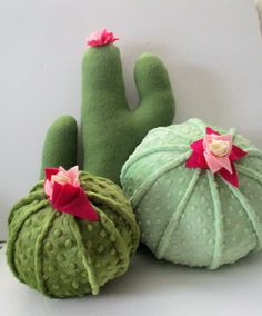 three green and pink decorative objects sitting on top of a white table next to each other